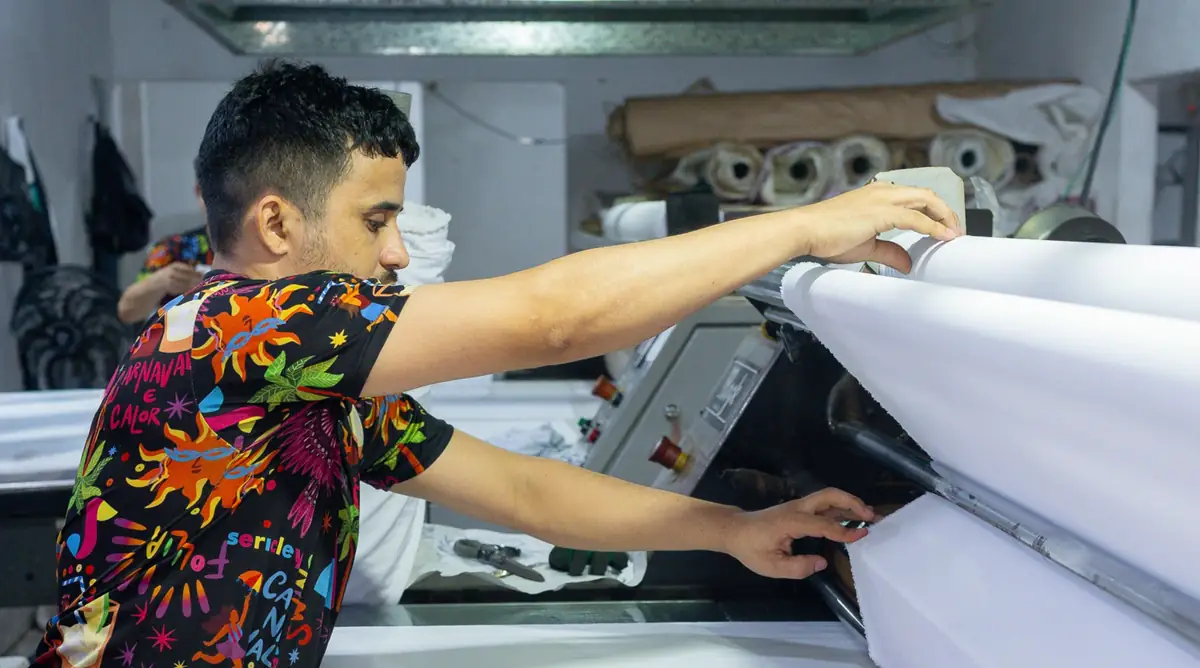 Operador alimentando a calandra com tecido branco na Sericley